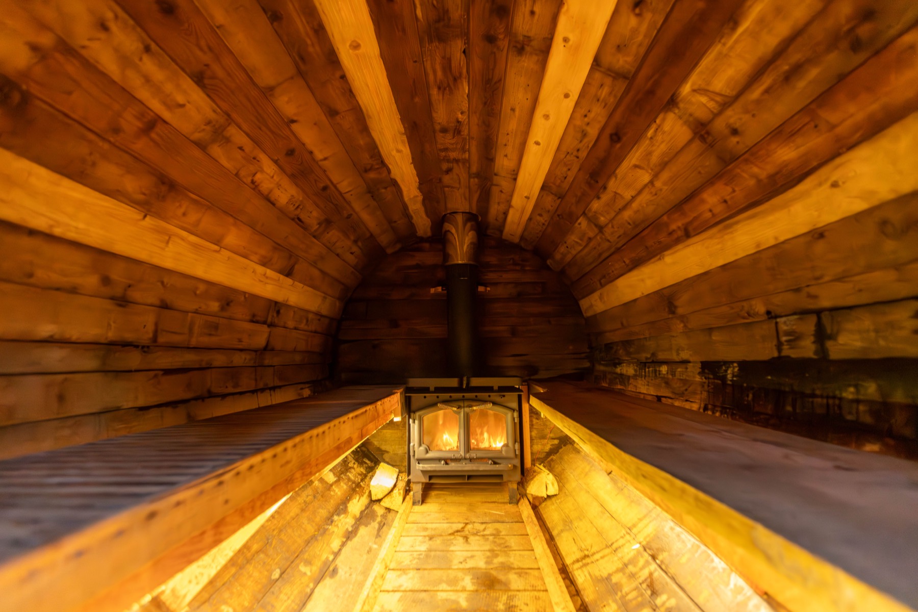 Inside the cedar barrel sauna, lit warm by the wood stove