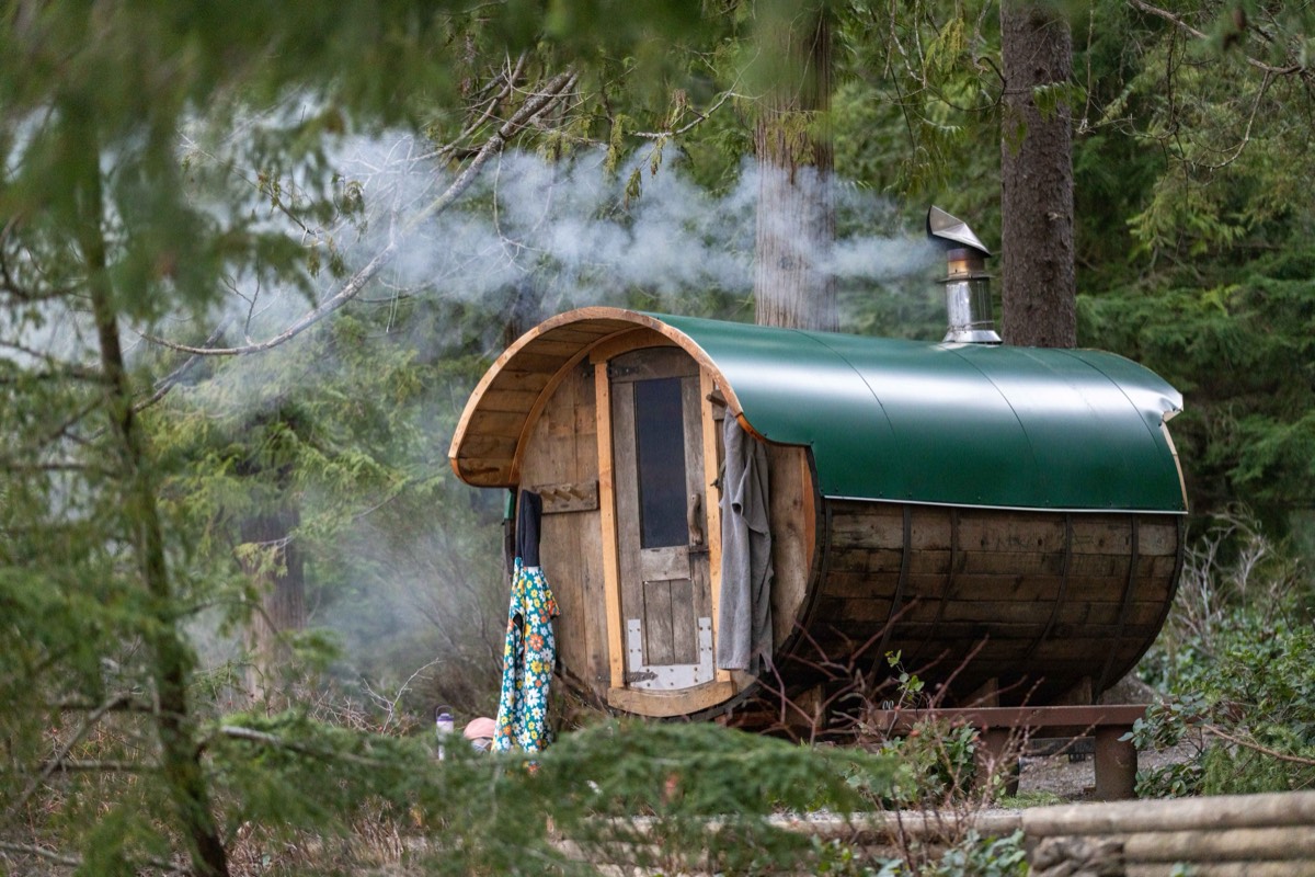 Steam and woodsmoke rising from the wood-fired barrel sauna